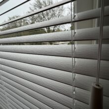 Grijze horizontale jaloezieën met een houtnerfstructuur.