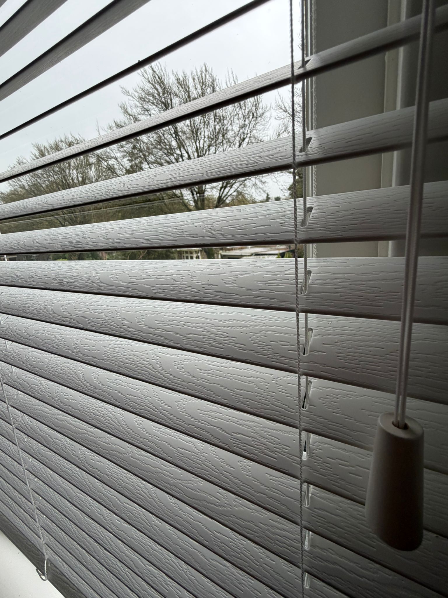 De voelbare houtnerfstructuur geeft deze grijze jaloezieën een warme, natuurlijke uitstraling. Een praktische en stijlvolle keuze die de look van echt hout combineert met het onderhoudsgemak van kunststof.