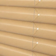 Close-up van de stof van een standaard plissé gordijn, met de kenmerkende harmonicavouw en zichtbare koordgaatjes.