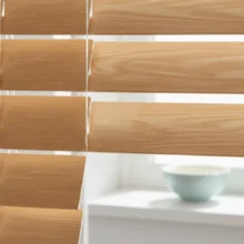 Close-up van PVC jaloezieën met een realistische houtlook-structuur, die de warme en natuurlijke uitstraling van hout tonen in een keuken.