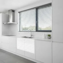 Strakke, moderne aluminium jaloezieën in een donkergrijze kleur, geïnstalleerd in een minimalistische keuken.