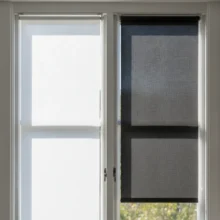 Vergelijkend beeld van een raam met links een witte jaloezie die zonlicht reflecteert en rechts een donkergrijze jaloezie die het licht absorbeert.