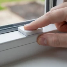 Een zelfklevende montageplaat wordt stevig op een kozijn gedrukt als boorvrije oplossing voor het ophangen van raamdecoratie.