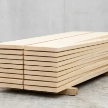 Stapel onbewerkte planken van abachi hout, die de lichte, egale crèmekleur en de fijne nerf van de houtsoort tonen.